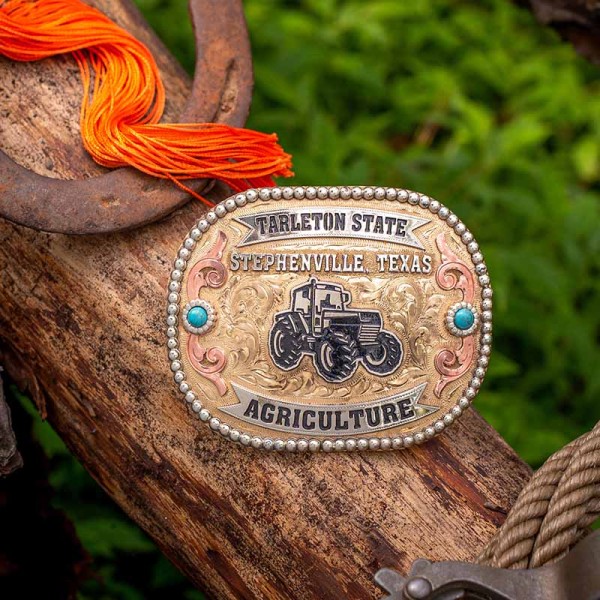 A custom farming belt buckle for Tartleton State, Stephenville, Texas, featuring a tractor figure on a golden jeweler's bronze hand engraved base